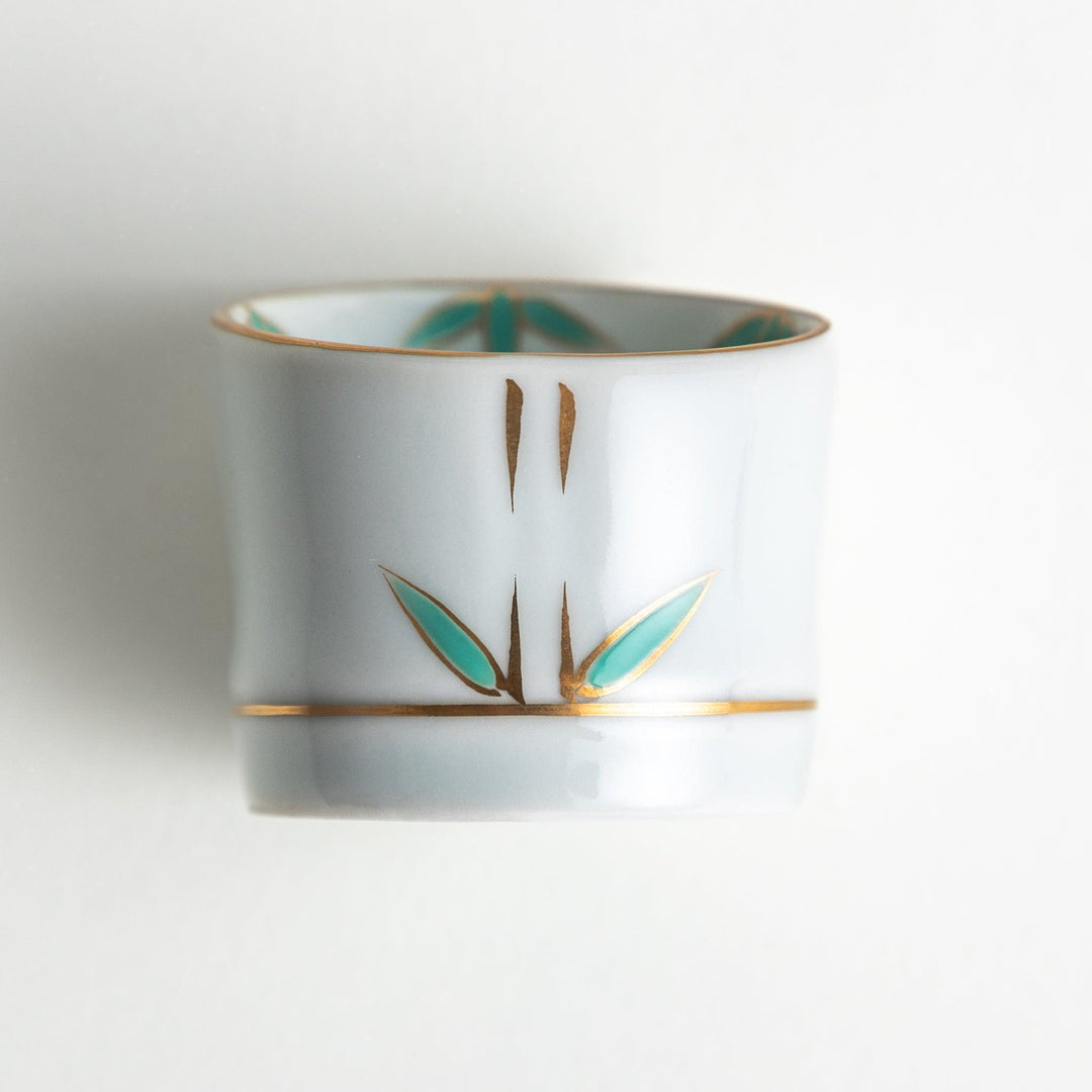 A small white bowl with a green bamboo leaf design and gold rim.