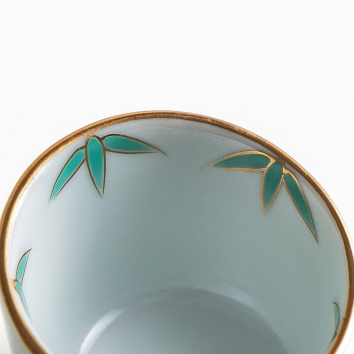 A small white bowl with a green bamboo leaf design and gold rim.