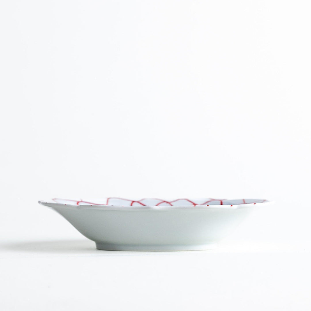 White dessert plate with a bowl shape featuring a blue or red net-like pattern