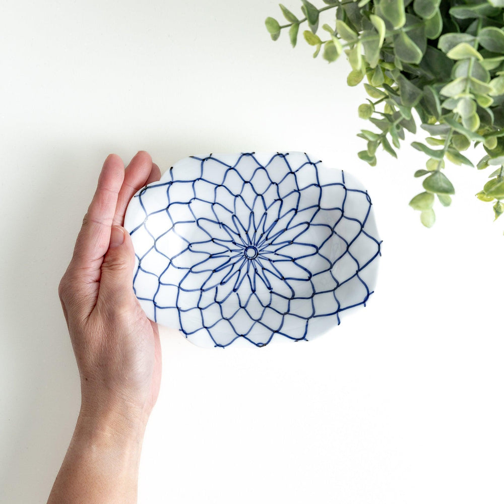 White dessert plate with a bowl shape featuring a blue or red net-like pattern