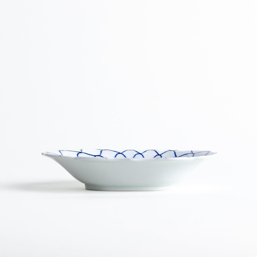 White dessert plate with a bowl shape featuring a blue or red net-like pattern