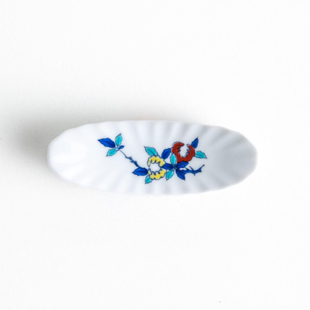 A ceramic chopstick rest with a floral design on top and a colorful geometric pattern along the sides.