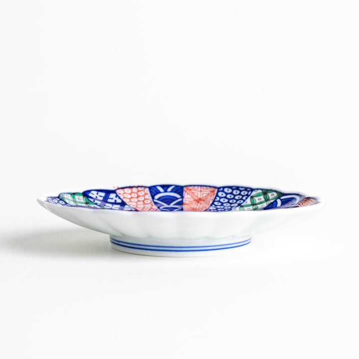 A sauce dish with a central floral motif and an intricate multicolored geometric pattern on the scalloped rim.