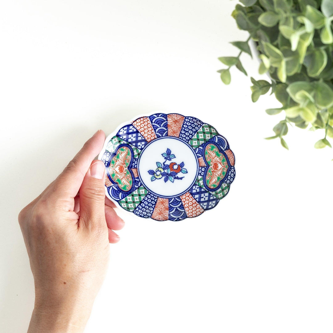 A sauce dish with a central floral motif and an intricate multicolored geometric pattern on the scalloped rim.