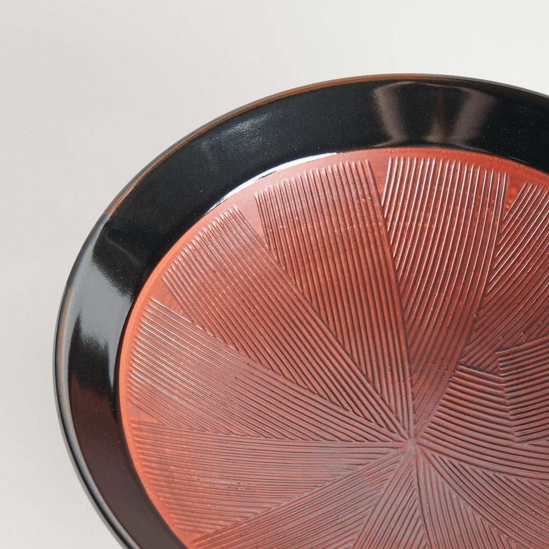 A shallow bowl with a smooth black exterior and a textured red interior.