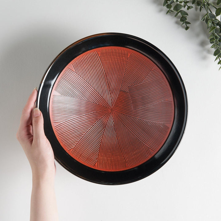 A shallow bowl with a smooth black exterior and a textured red interior.