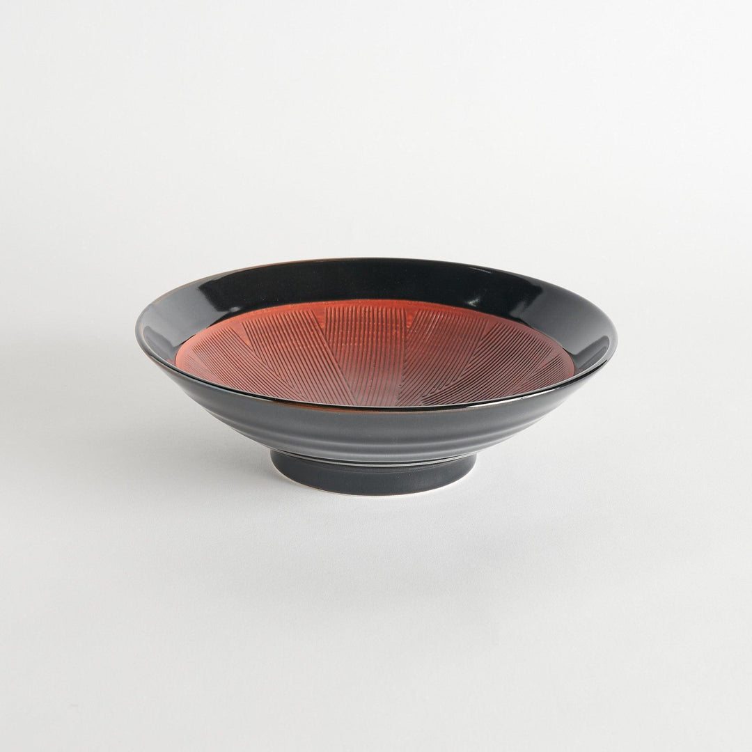 A shallow bowl with a smooth black exterior and a textured red interior.