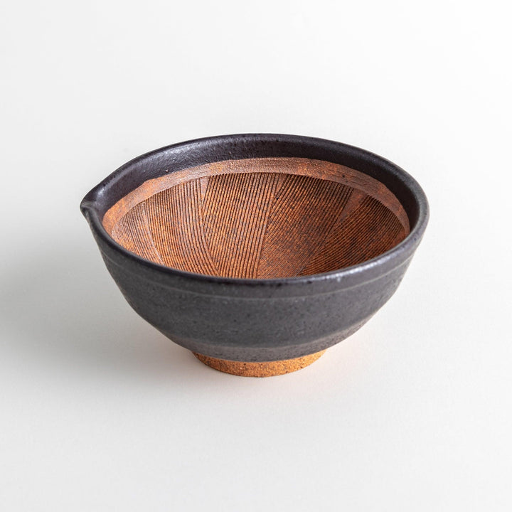 A small, black ceramic bowl with a rough texture and a natural, unglazed bottom.
