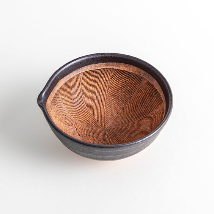 A small, black ceramic bowl with a rough texture and a natural, unglazed bottom.
