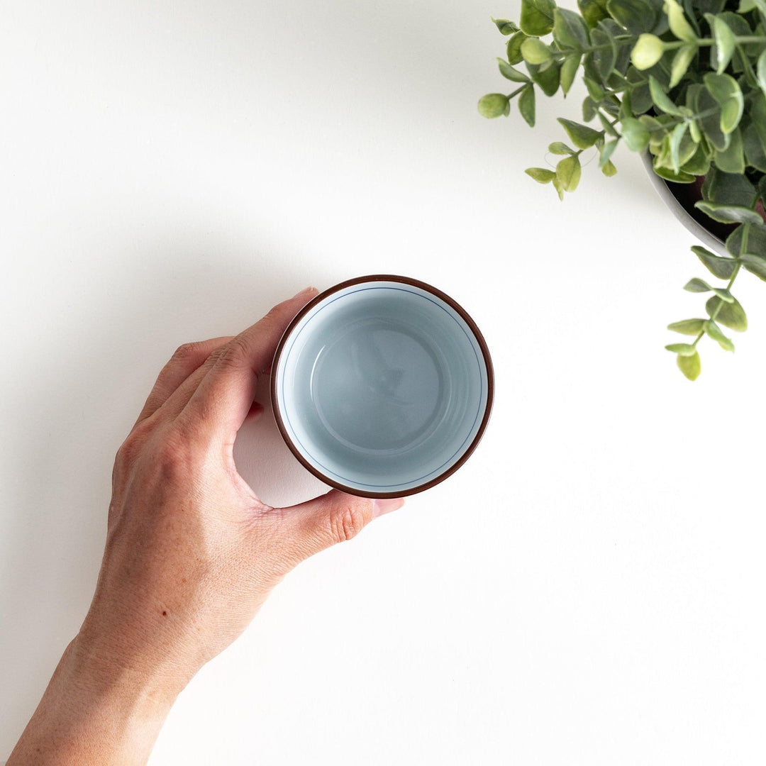 A small cylindrical cup featuring a dense blue leaf pattern on a white base.