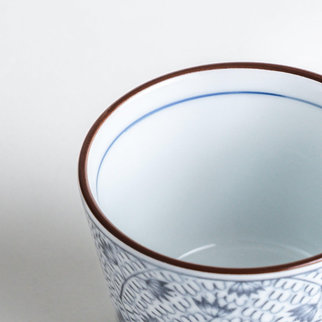 A small cylindrical cup featuring a dense blue leaf pattern on a white base.