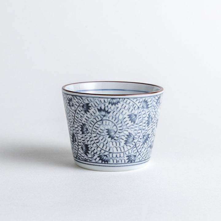 A small cylindrical cup featuring a dense blue leaf pattern on a white base.