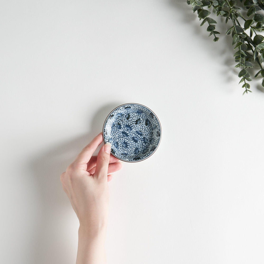 A small saucer adorned with detailed blue leaf patterns on a white background.