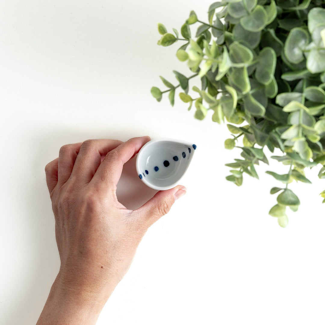 A small, curved condiment bowl with minimal blue dot accents.