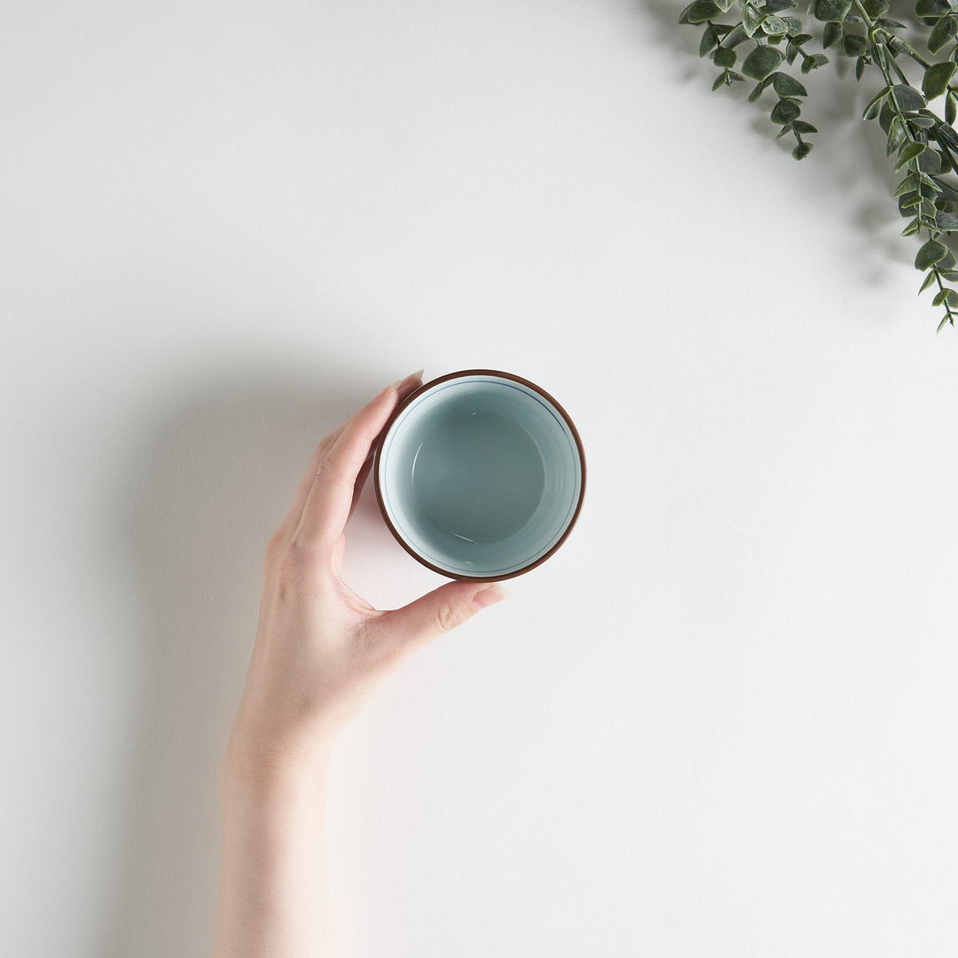 A small cylindrical cup with a bold blue flower pattern on a white base.