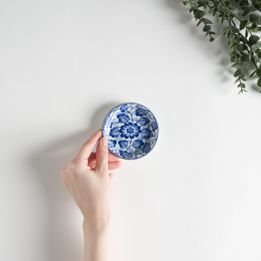 A round saucer featuring a delicate blue floral design on a white background.