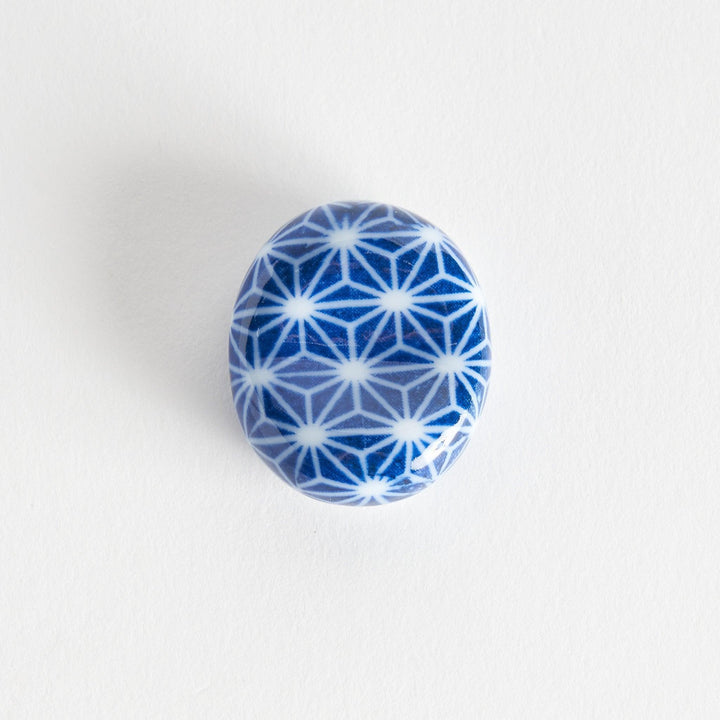 A blue and white rounded ceramic chopstick rest with a starburst pattern.