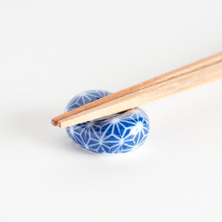 A blue and white rounded ceramic chopstick rest with a starburst pattern.