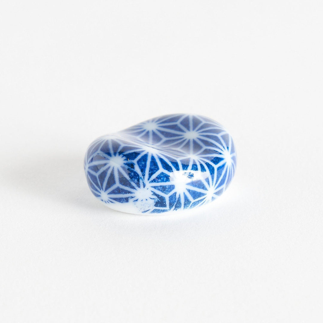 A blue and white rounded ceramic chopstick rest with a starburst pattern.