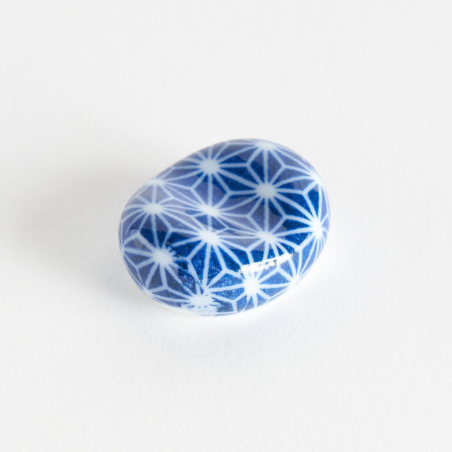 A blue and white rounded ceramic chopstick rest with a starburst pattern.