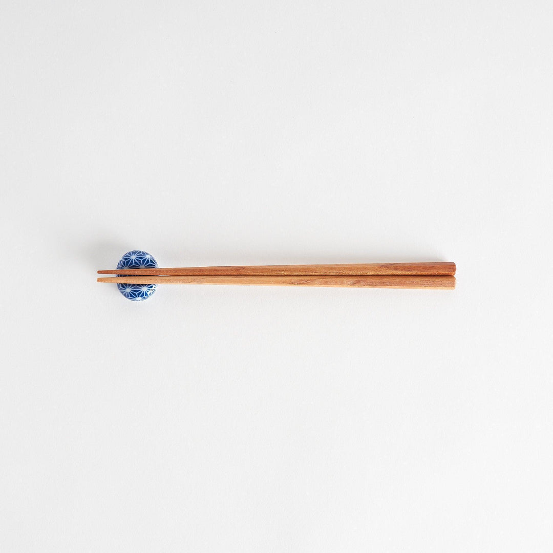 A blue and white rounded ceramic chopstick rest with a starburst pattern.