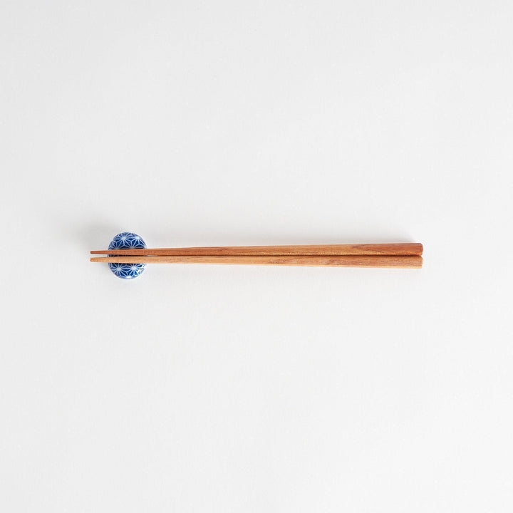 A blue and white rounded ceramic chopstick rest with a starburst pattern.