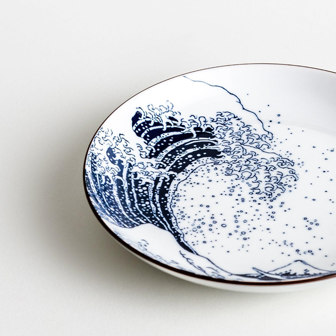 A round plate featuring the famous "Great Wave" artwork in blue on a white background.