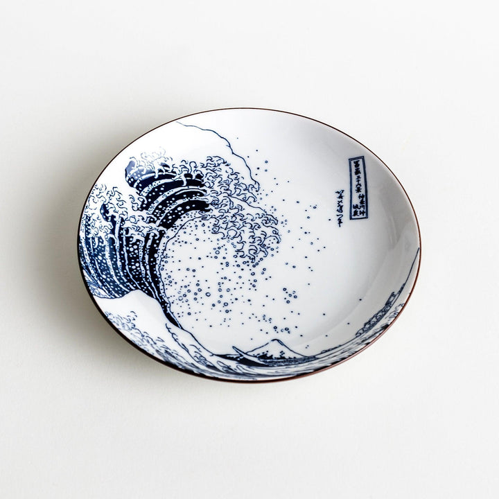 A round plate featuring the famous "Great Wave" artwork in blue on a white background.