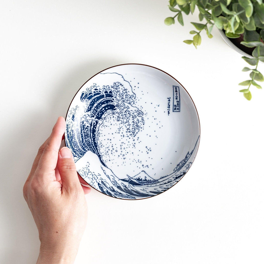 A round plate featuring the famous "Great Wave" artwork in blue on a white background.