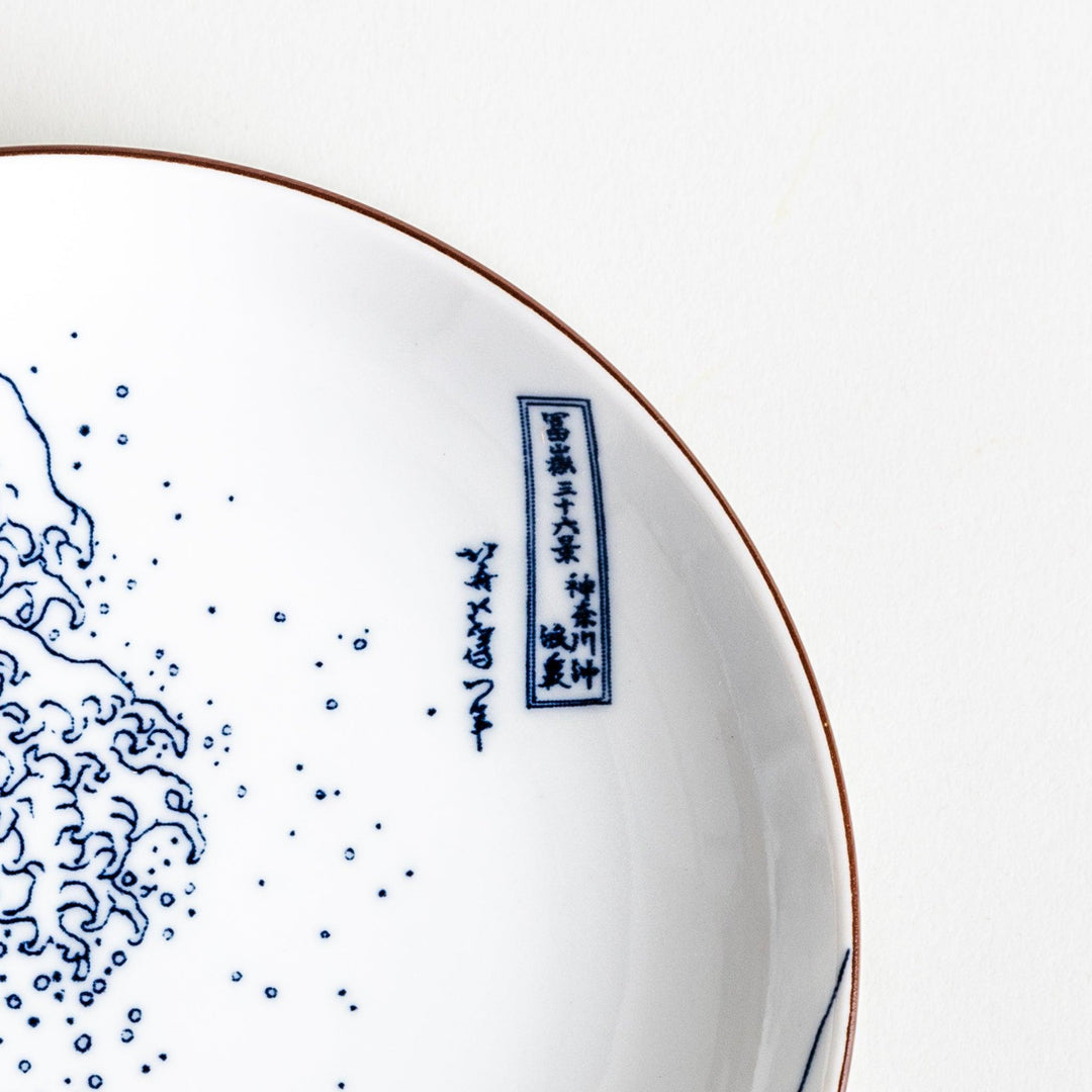 A round plate featuring the famous "Great Wave" artwork in blue on a white background.