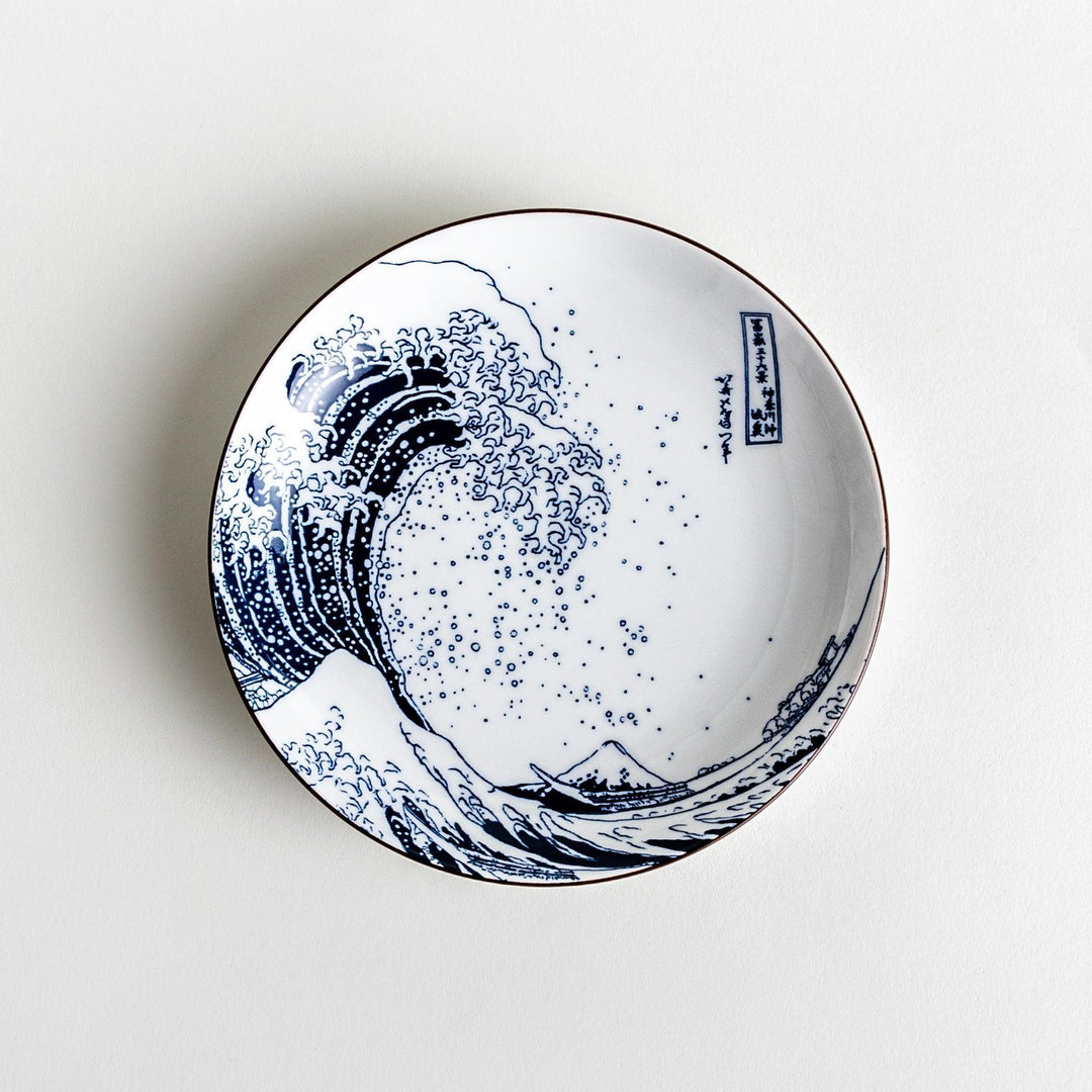 A round plate featuring the famous "Great Wave" artwork in blue on a white background.