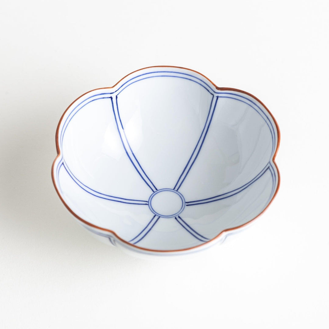 A white ceramic bowl with a floral shape, featuring delicate blue lines and an orange rim.