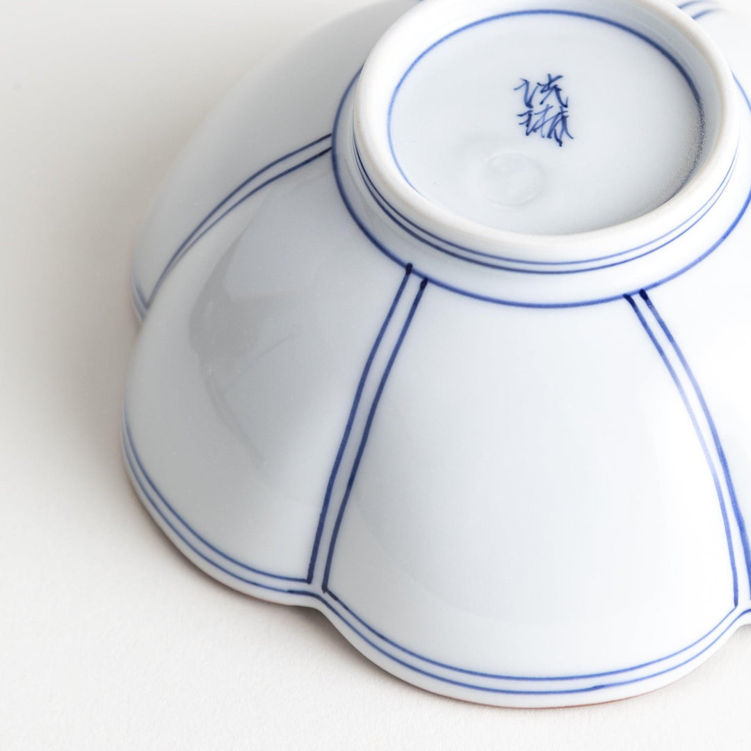 A white ceramic bowl with a floral shape, featuring delicate blue lines and an orange rim.