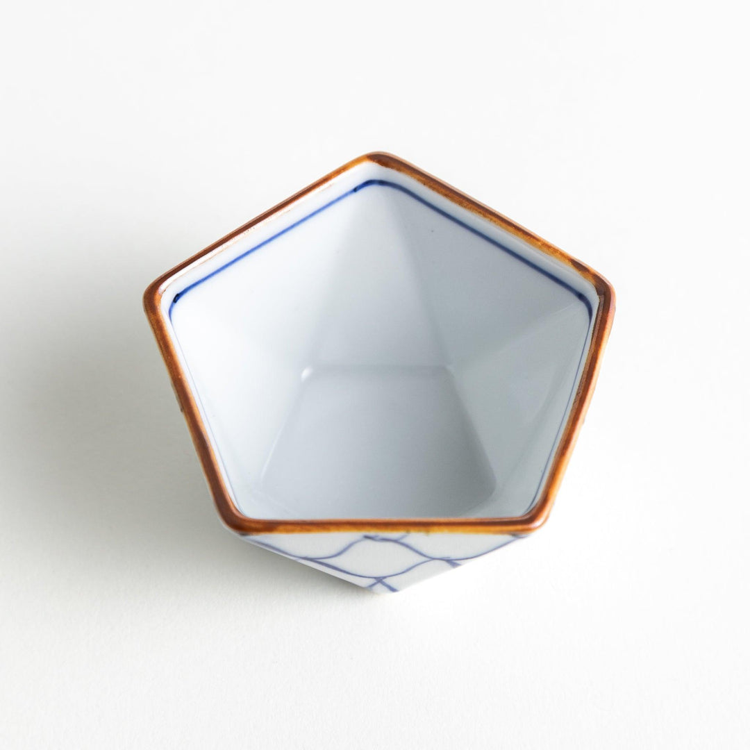 A small, white pentagonal bowl adorned with a blue scale pattern, highlighted with a brown rim.