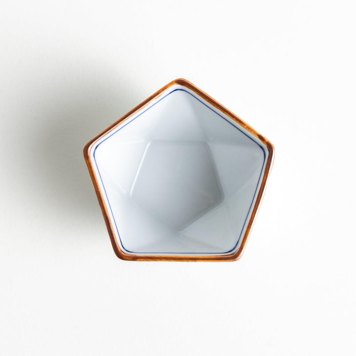 A small, white pentagonal bowl adorned with a blue scale pattern, highlighted with a brown rim.