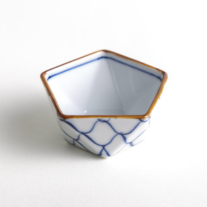 A small, white pentagonal bowl adorned with a blue scale pattern, highlighted with a brown rim.