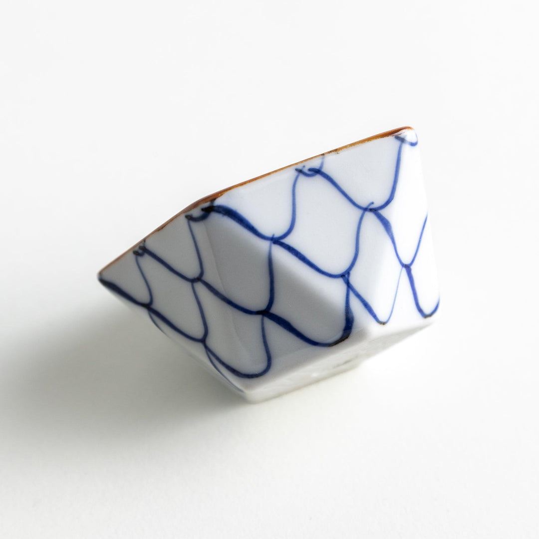 A small, white pentagonal bowl adorned with a blue scale pattern, highlighted with a brown rim.