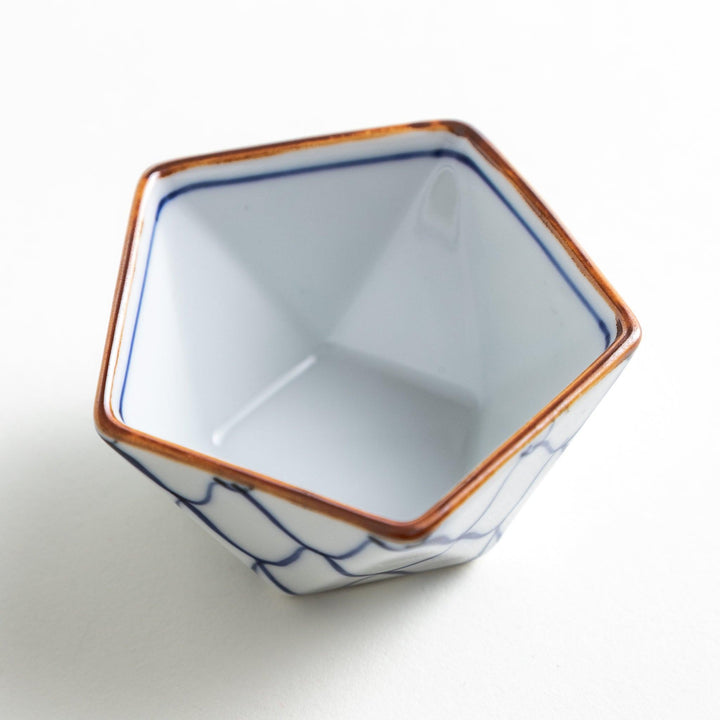 A small, white pentagonal bowl adorned with a blue scale pattern, highlighted with a brown rim.