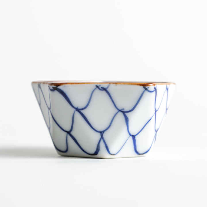 A small, white pentagonal bowl adorned with a blue scale pattern, highlighted with a brown rim.