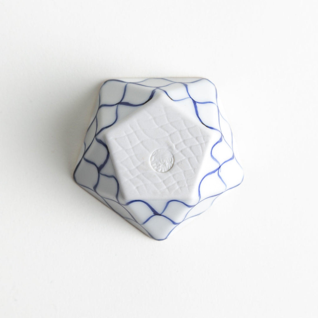 A small, white pentagonal bowl adorned with a blue scale pattern, highlighted with a brown rim.