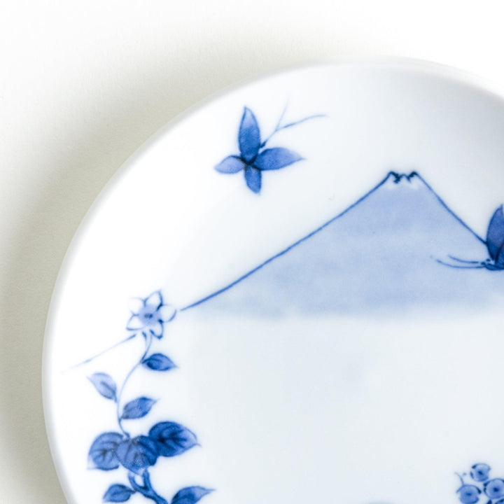 Round plate with a blue and white Mount Fuji and butterfly scene.