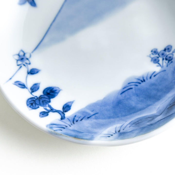 Round plate with a blue and white Mount Fuji and butterfly scene.