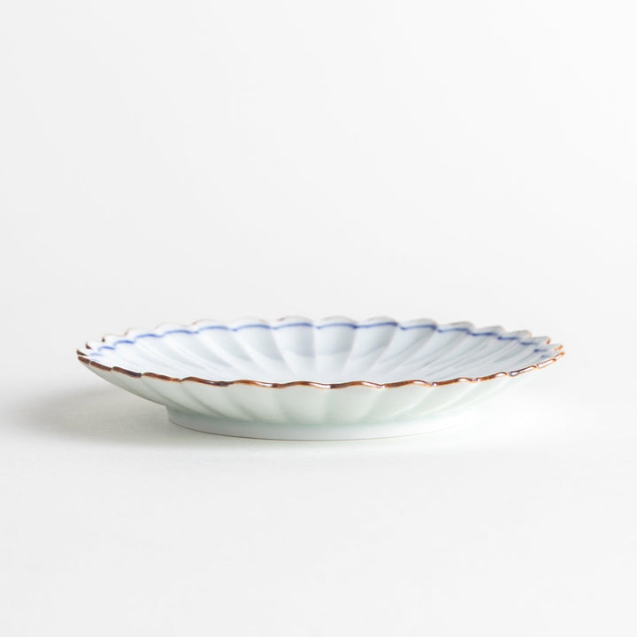 A small round plate with a scalloped edge and a delicate blue rim