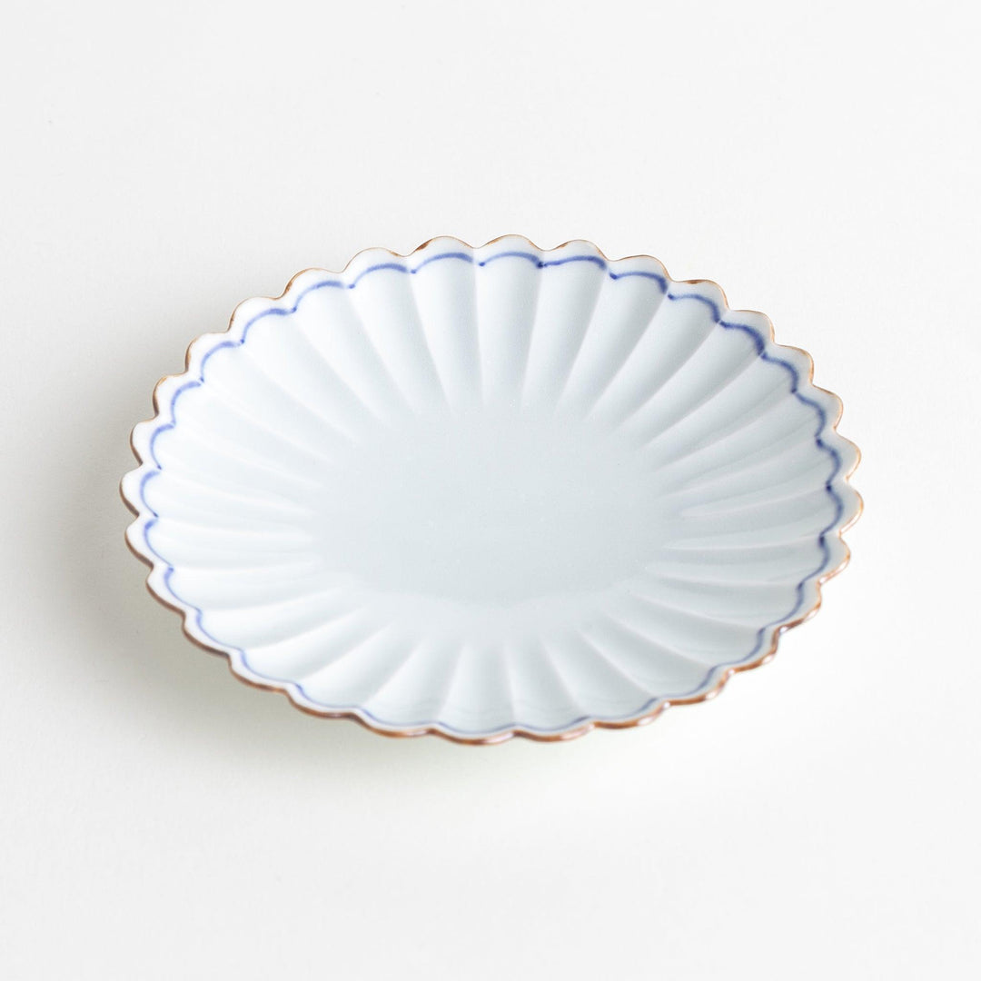 A small round plate with a scalloped edge and a delicate blue rim