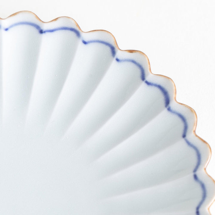 A small round plate with a scalloped edge and a delicate blue rim