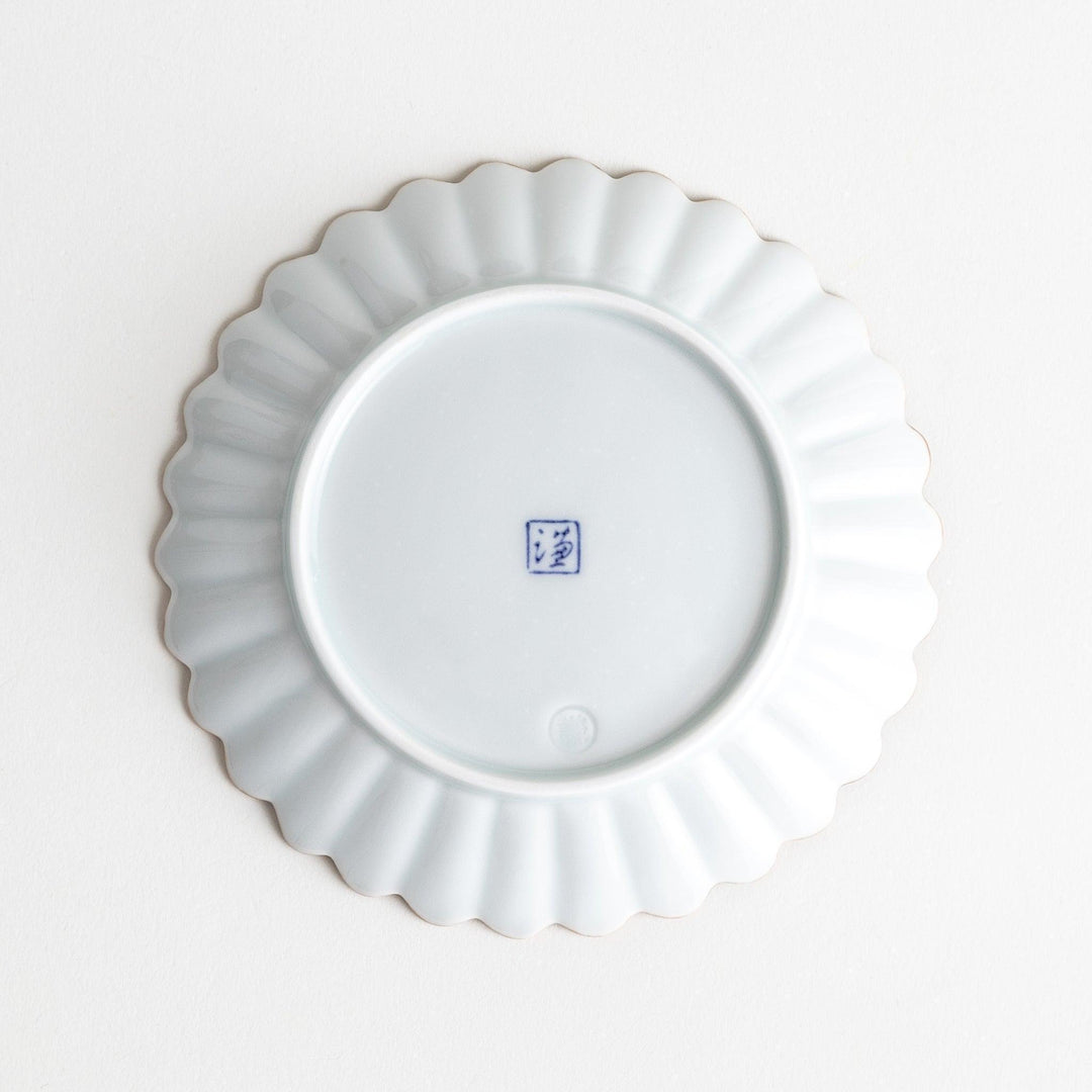 A small round plate with a scalloped edge and a delicate blue rim