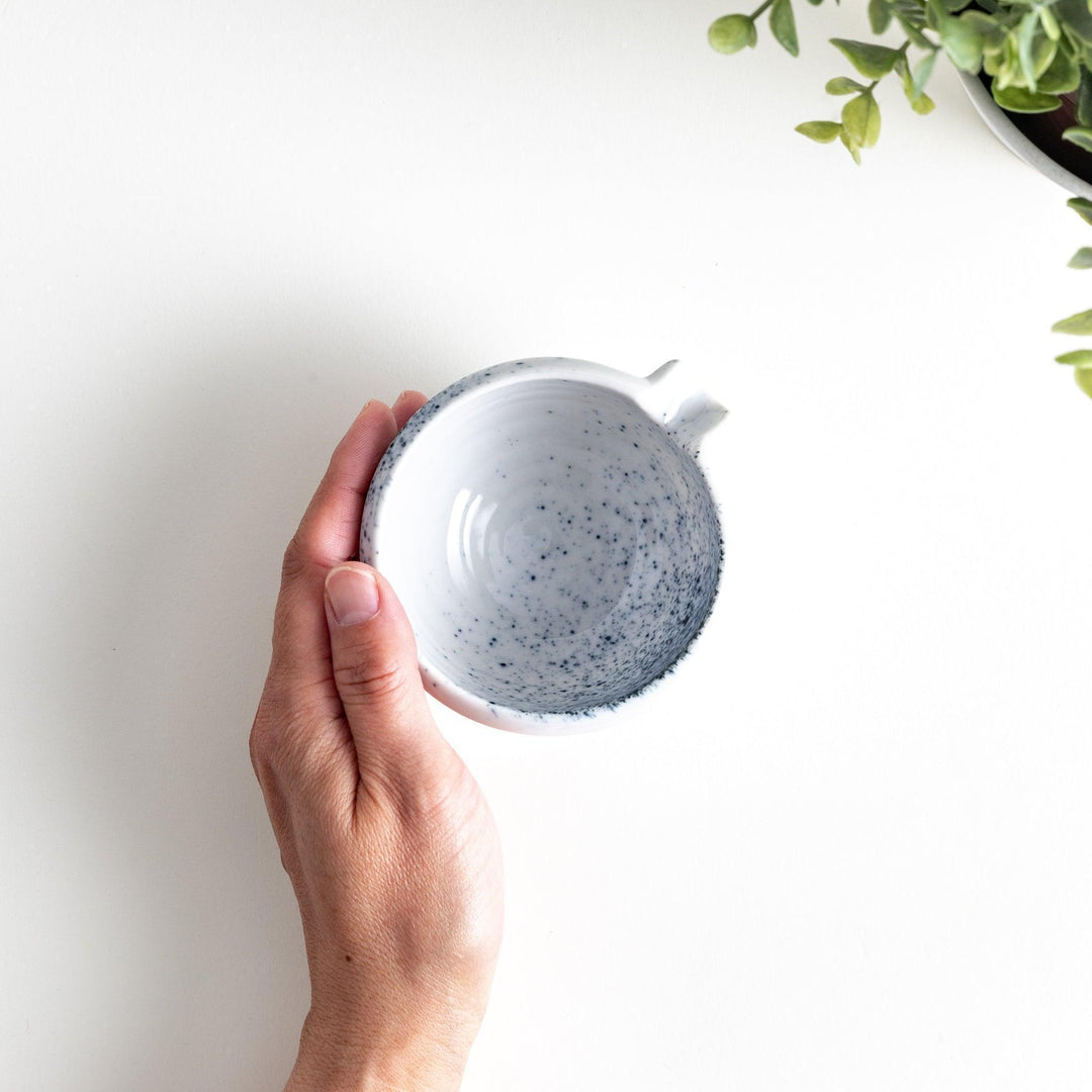 A small condiment bowl with blue speckled patterns on a white background.