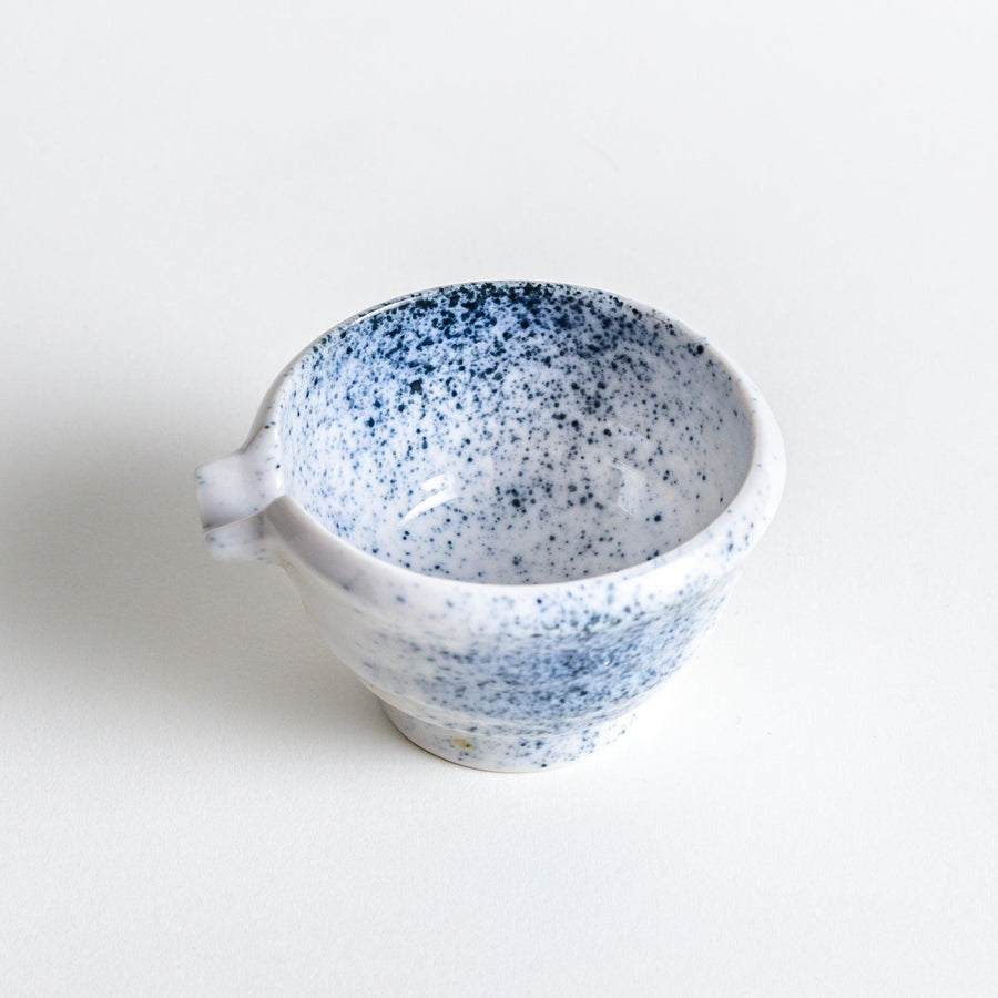 A small condiment bowl with blue speckled patterns on a white background.