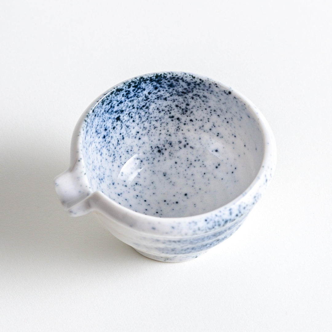 A small condiment bowl with blue speckled patterns on a white background.