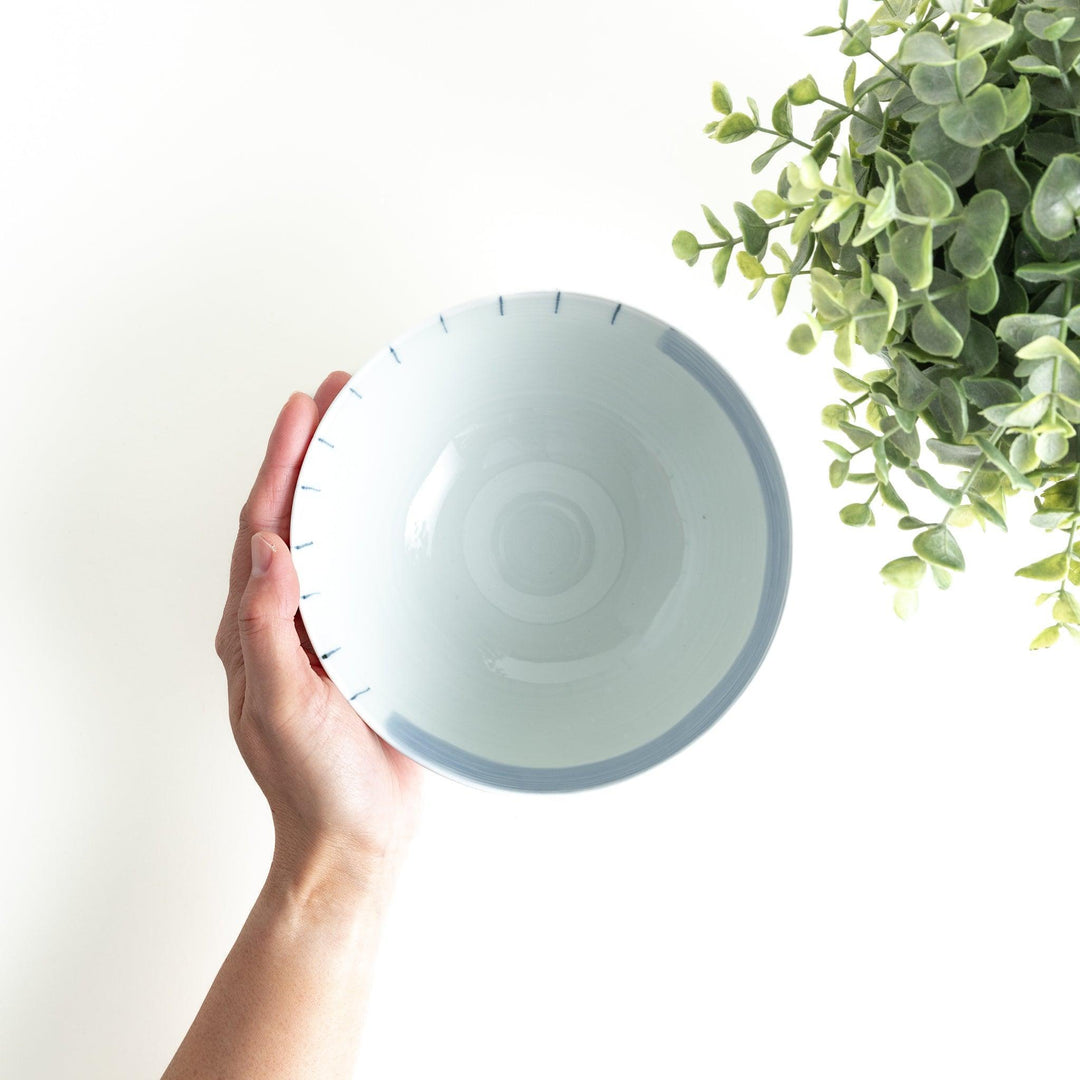 A white ceramic bowl with vertical blue stripes in a simple, clean design.